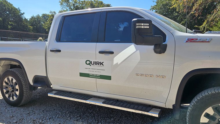 Quirk Lawn & Property Chevrolet 2500 HD work truck with company door signage.
