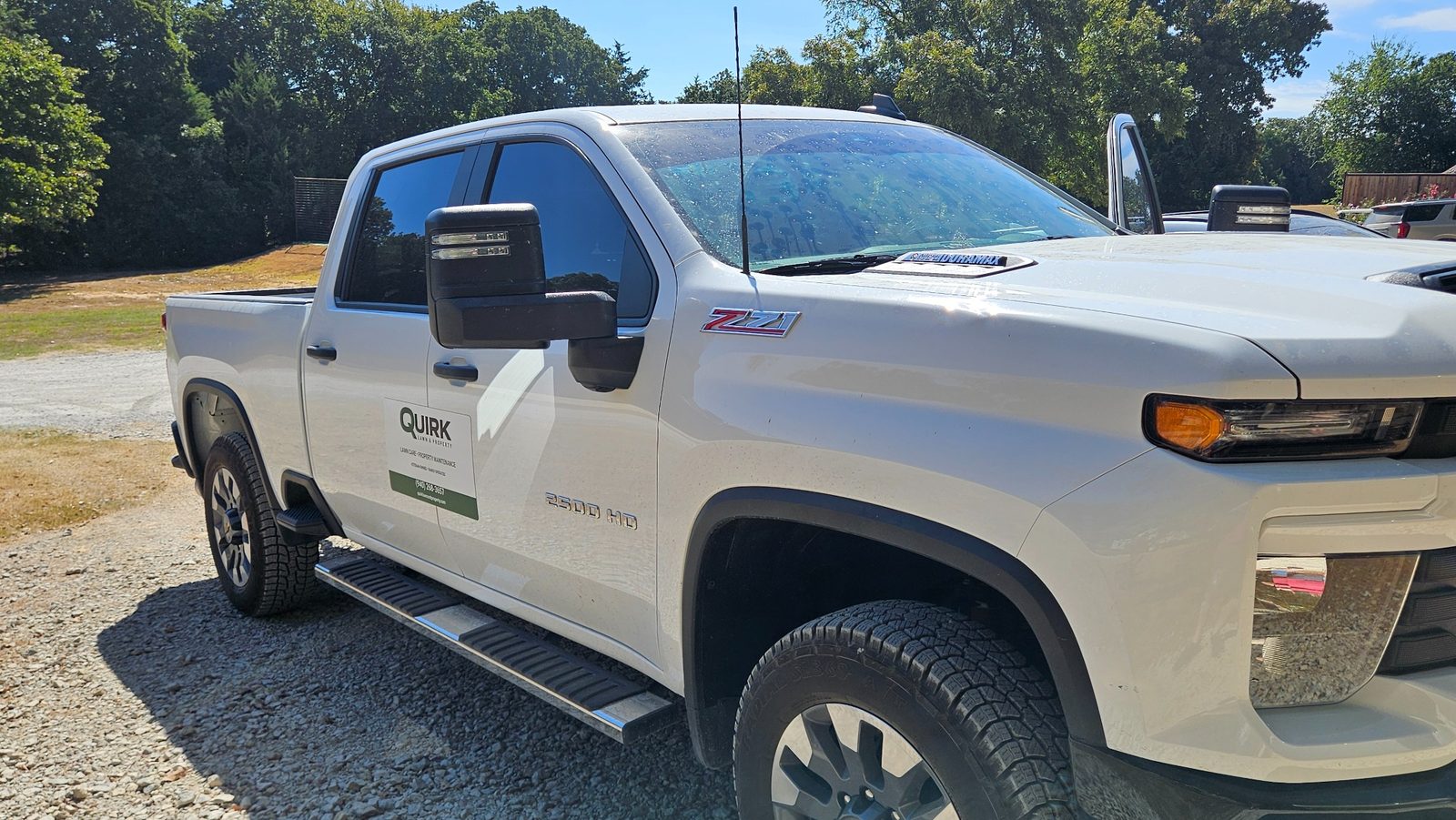 Quirk Lawn & Property Chevrolet 2500 HD work truck with business signage.